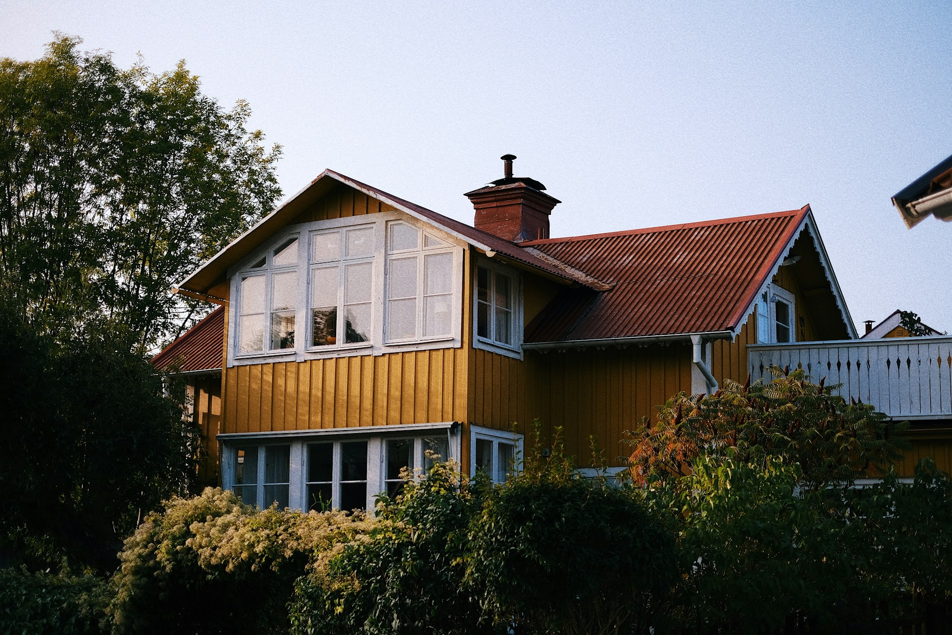 a yellow house with a red roof and white windows